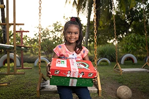 Little girl holding shoebox gift.